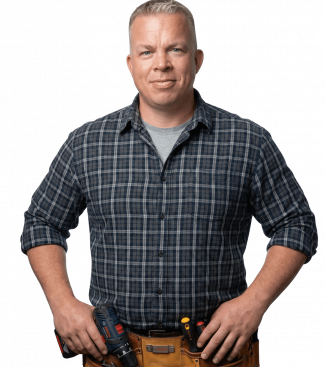 Freundlicher und professioneller Handwerker in Arbeitskleidung mit Werkzeuggürtel vor hellem Hintergrund