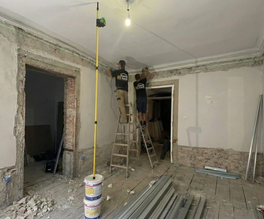 Zwei Handwerker entfernen alten Putz von Ziegelwänden bei einer Altbausanierung in Mannheim