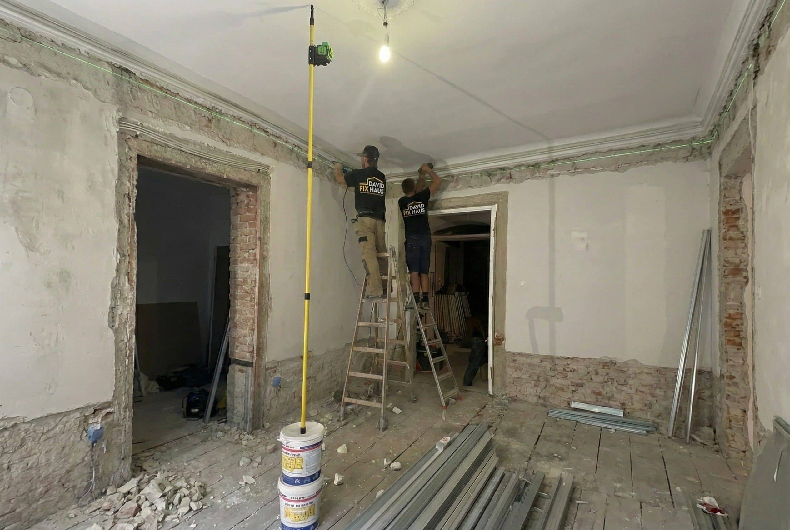 Zwei Handwerker entfernen alten Putz von Ziegelwänden bei einer Altbausanierung in Mannheim