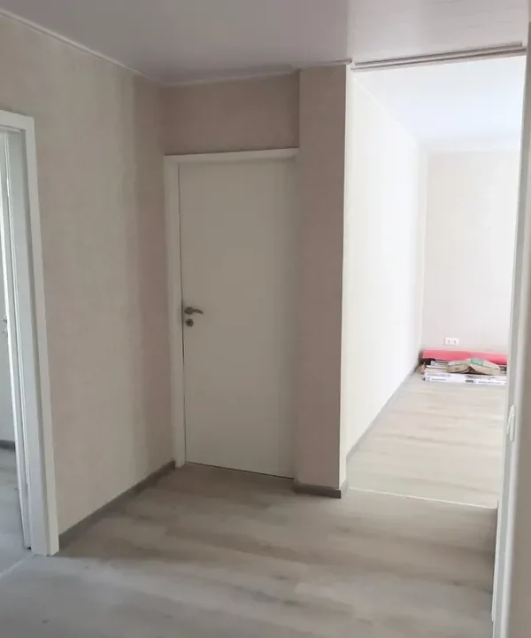 Flur einer renovierten Wohnung mit neuem Vinylboden in Eichenoptik, weißen Innentüren mit Zargen und neu tapezierten Wänden