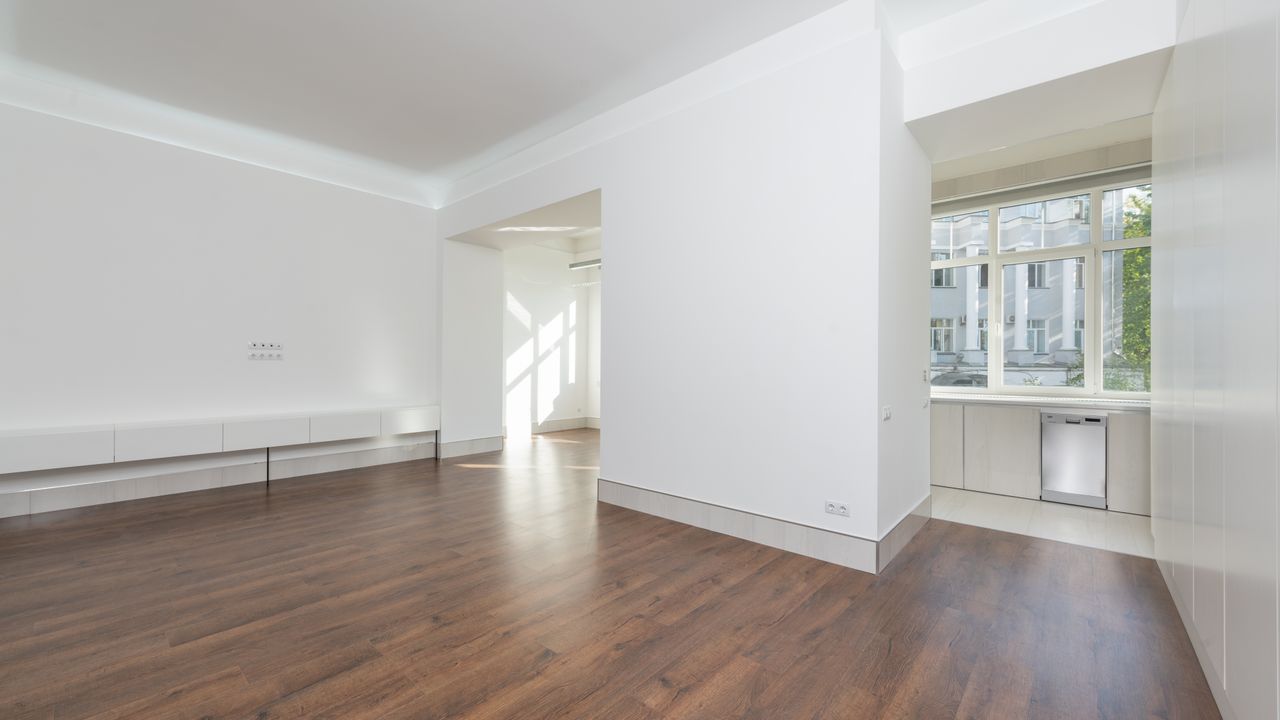 Renovierte, leere Wohnung mit frisch gestrichenen weißen Wänden und dunklem Holzboden