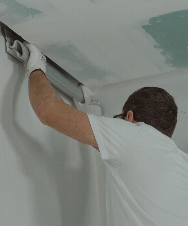 Trockenbauer richtet am Übergang von Decke und Wand ein Profil mit der Wasserwaage aus